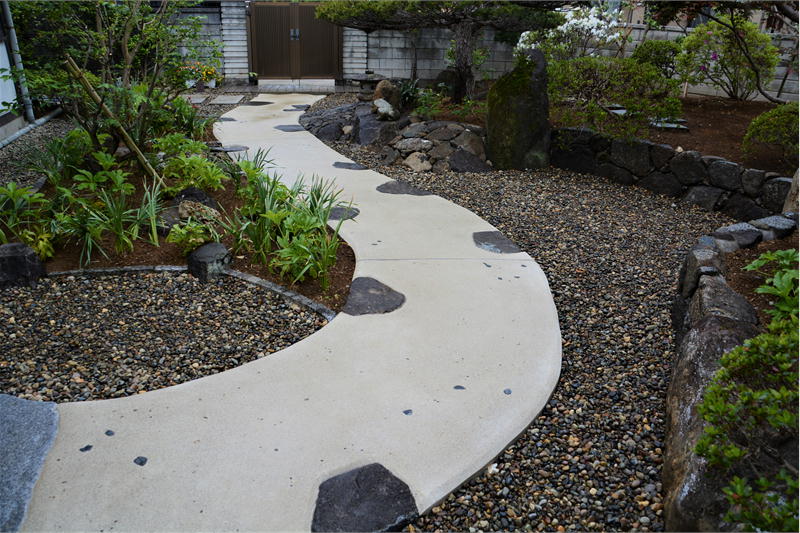 庭にあった筑波石を所々に配し曲線を描くアプローチ｜玄関からの眺め