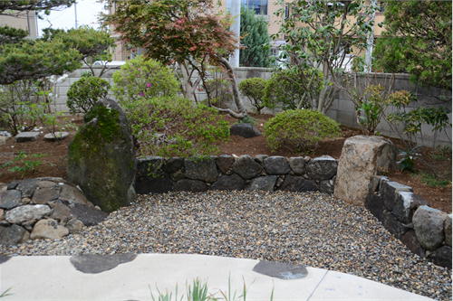 アプローチの曲線に合わせて石積みも曲線とする｜筑波石による石積みによって庭の高低差を活かす