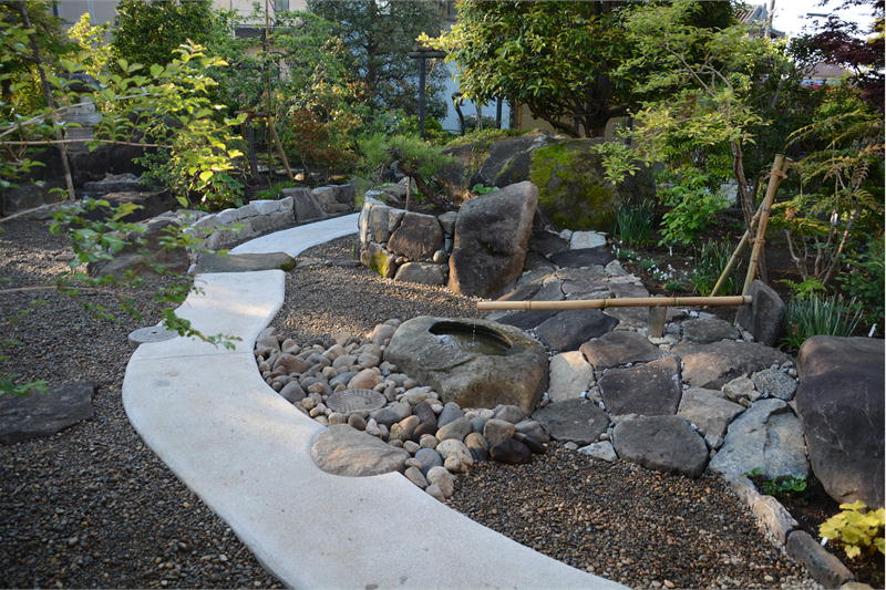 母屋から離れ家へと続く洗い出しによるアプローチと形のよい自然形のつくばい/石を使った庭のリフォーム、茨城